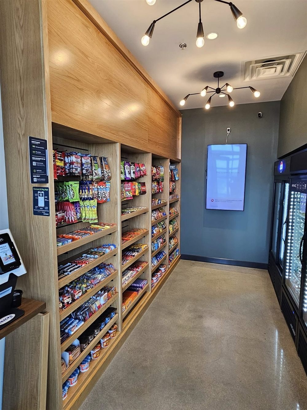 Micro market with wood shelving, coolers, and self-checkout kiosk